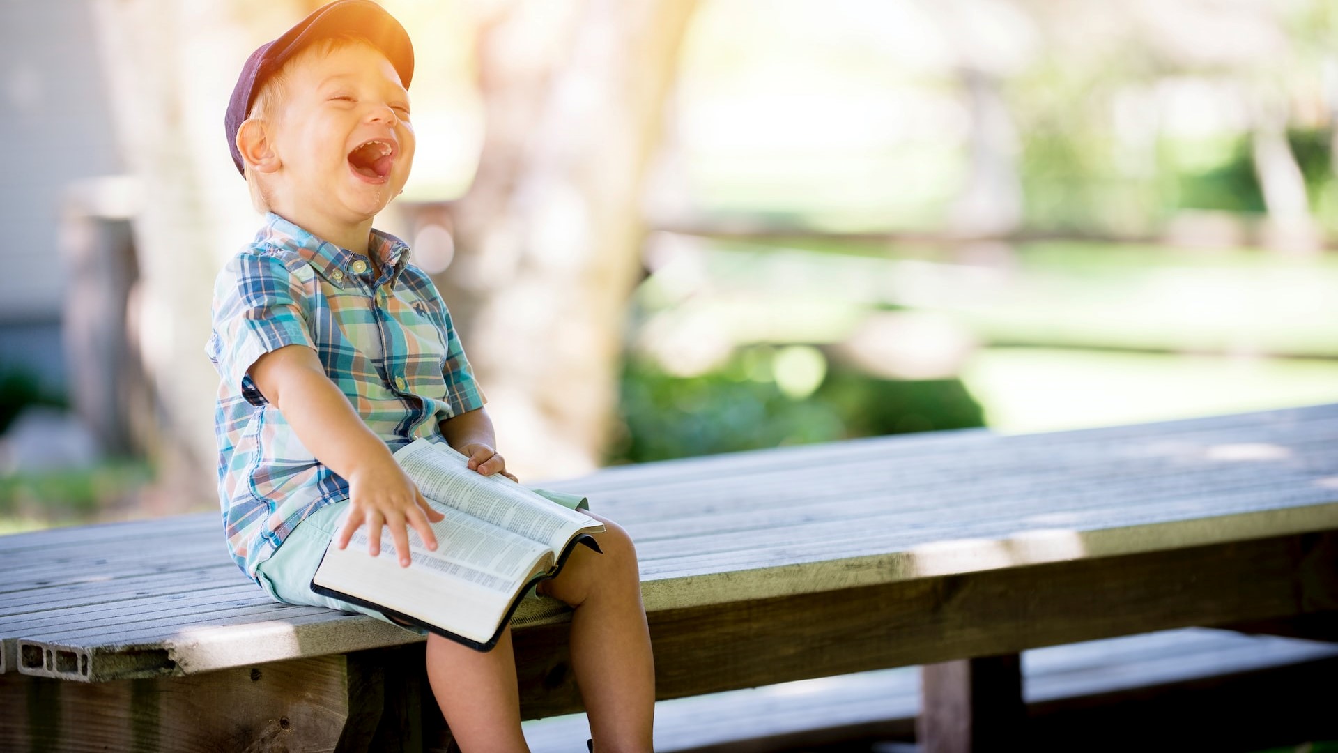 Kid holding a book laughing | Kids Car Donations