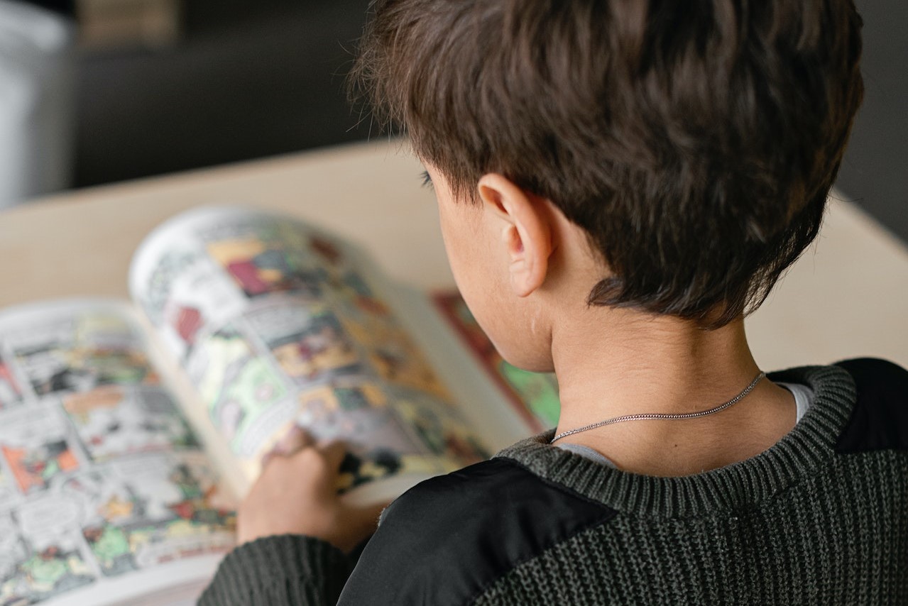 Boy in Black Sweater Reading a Comics | Kids Car Donations