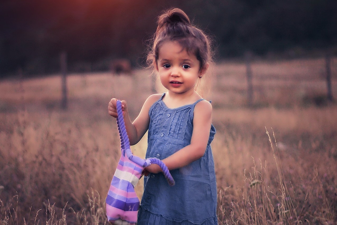 Girl in Blue Dress Standing on Grass Field during Sunset | Kids Car Donations