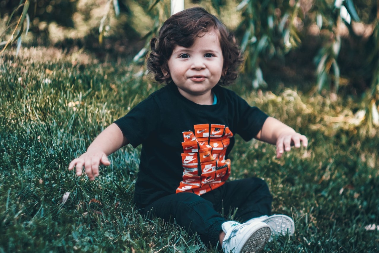 Cute Boy Sitting on Green Grass | Kids Car Donations