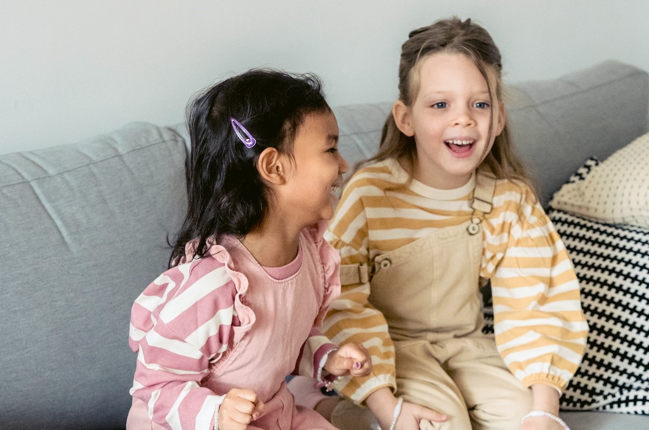 Playful diverse girls laughing on sofa | Kids Car Donations