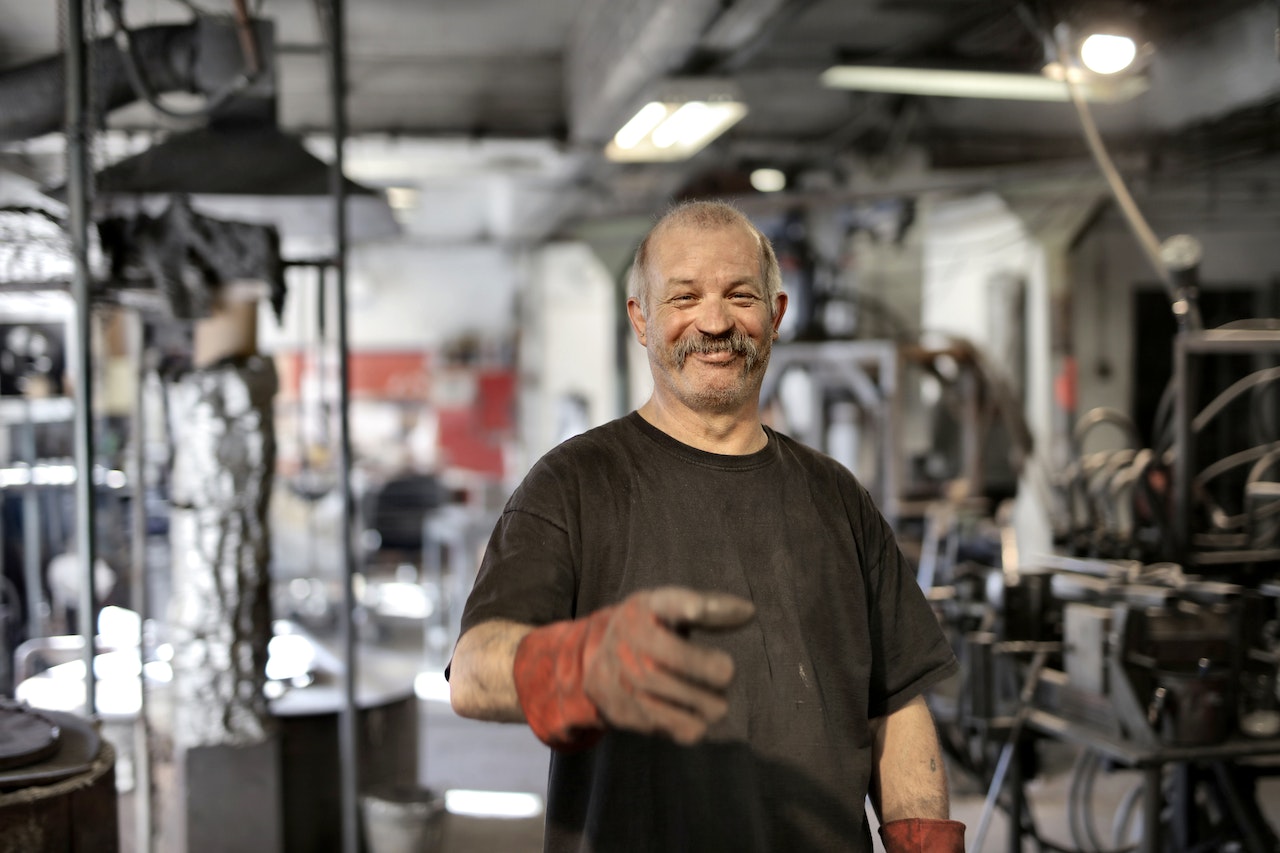 Happy elderly worker smiling in workshop | Kids Car Donations