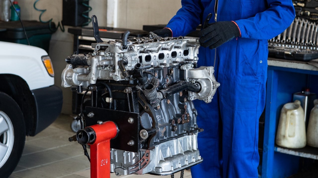 Man wearing a blue suit checking a car engine | Kids Car Donations