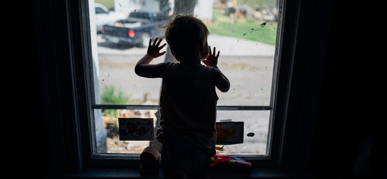 Silhouette of little boy looking out window | Kids Car Donations