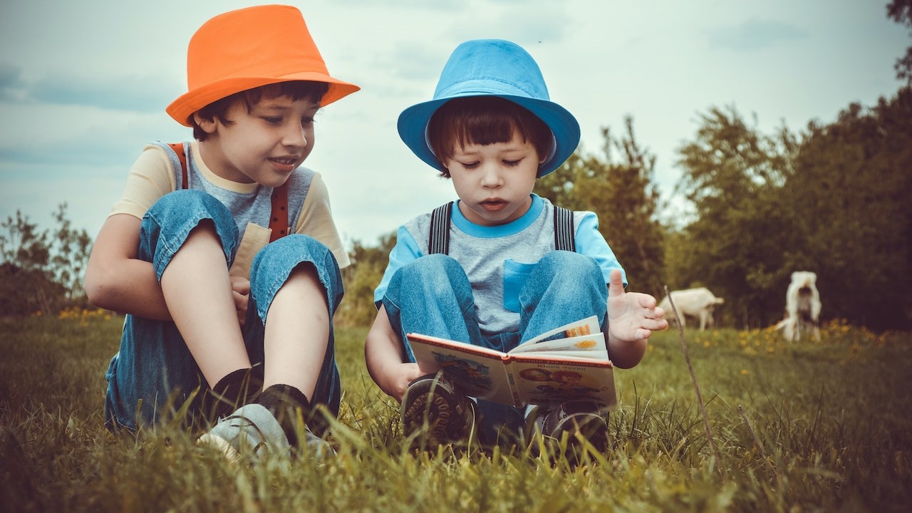 Kids sitting on the grass reading a book | Kids Car Donations