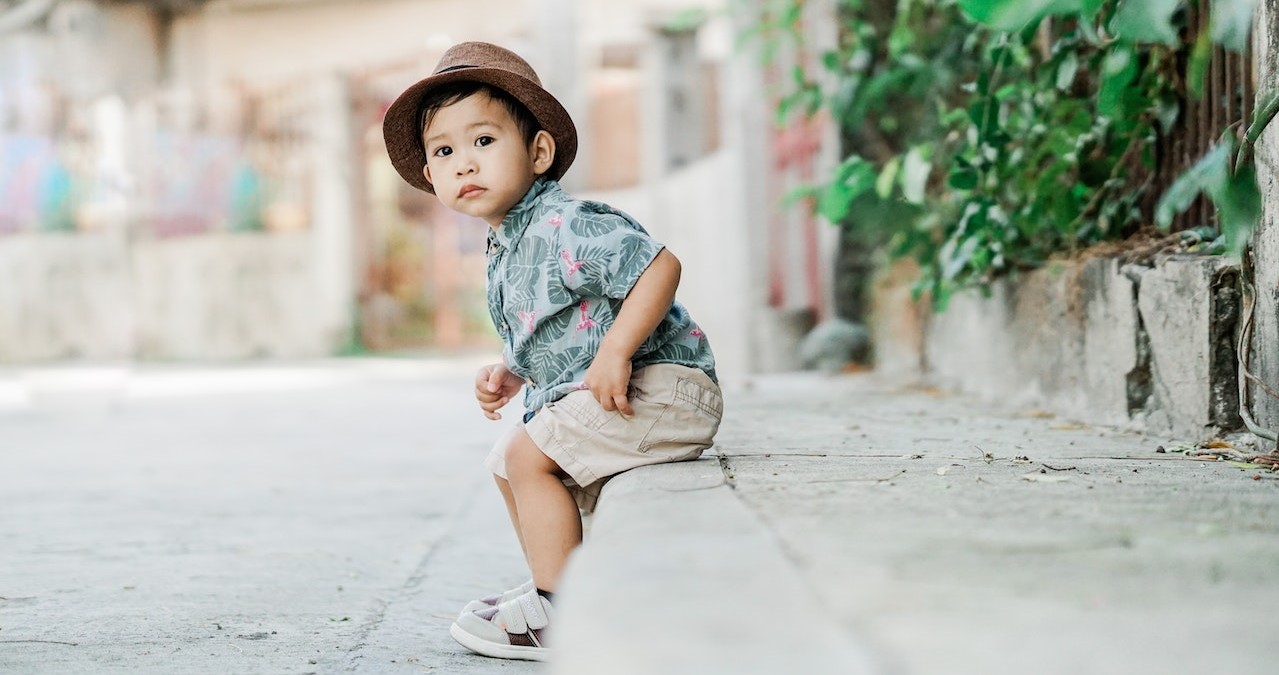 Boy Wearing Hat Sitting on Sidewalk | Kids Car Donations
