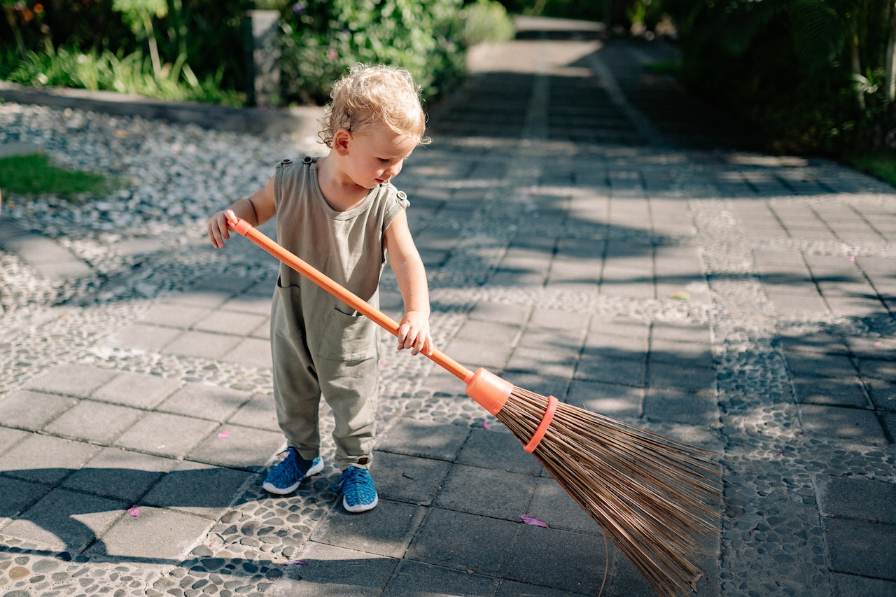 Charming Child Sweeping Concrete Pavement with Broomstick | Kids Car Donations