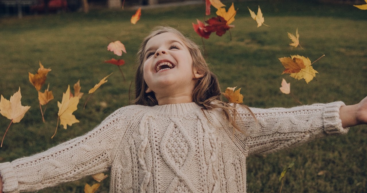 Girl Wearing Knitted Sweater Standing Outside With Leave | Kids Car Donations