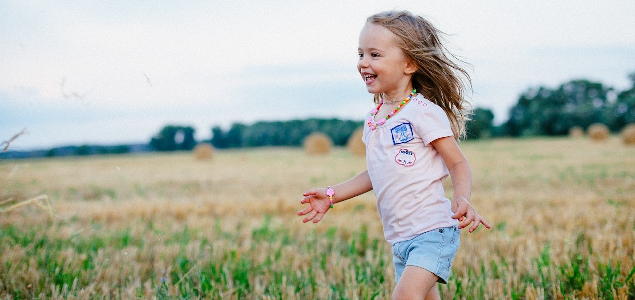 Smiling Girl Running on Green Field | Kids Car Donations