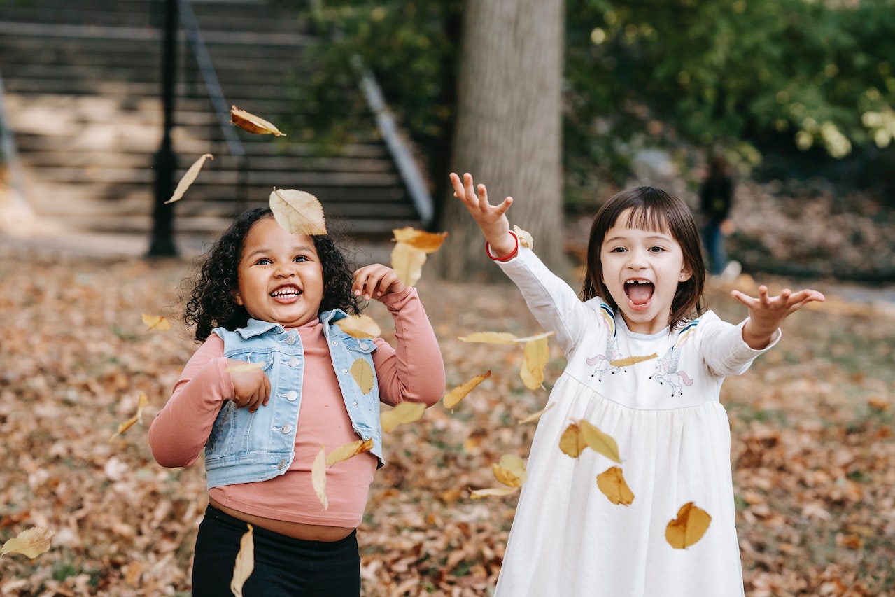 Happy kids throwing foliage in park | Kids Car Donations