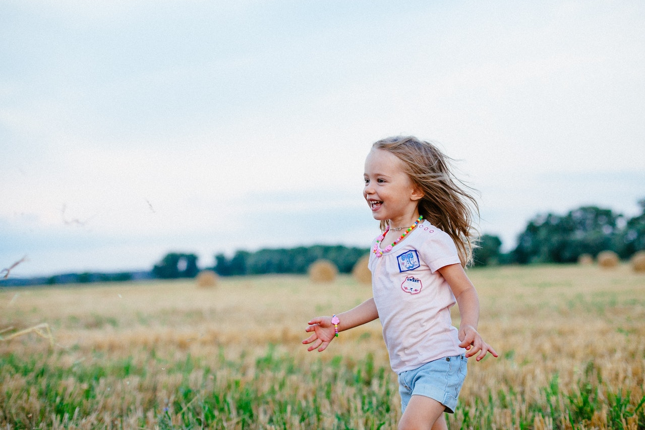 Smiling Girl Running Towards Left on Green Field | Kids Car Donations