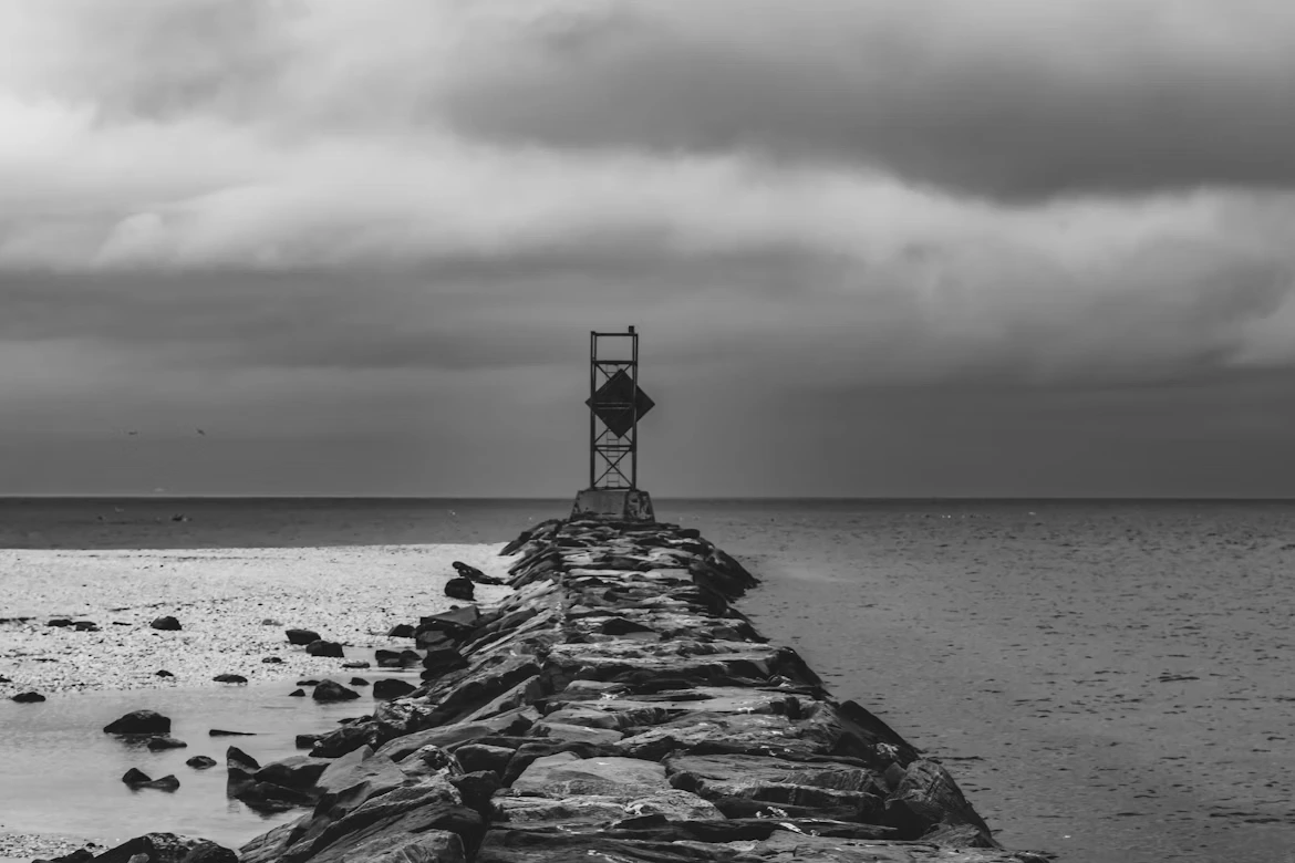 Black and white photo of a long pier stretching into the water at dusk in Long Island, New York