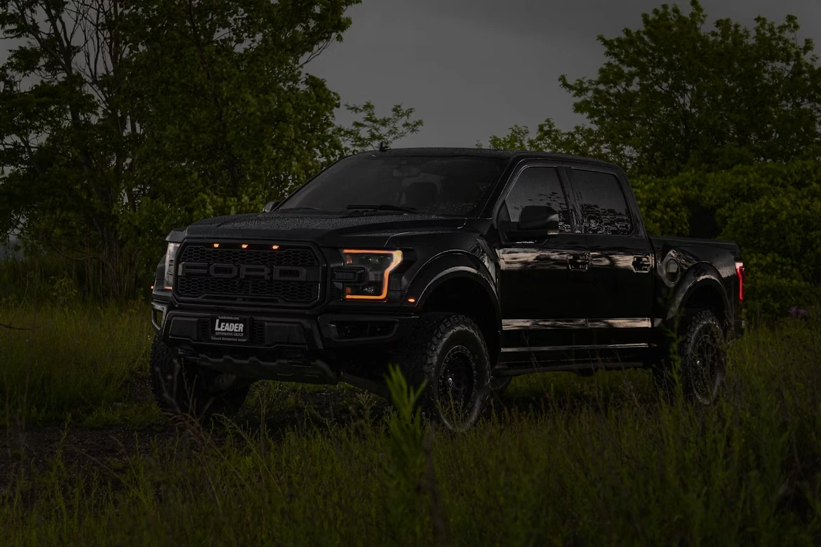 Black Ford pickup truck parked in a field at night under a dark sky