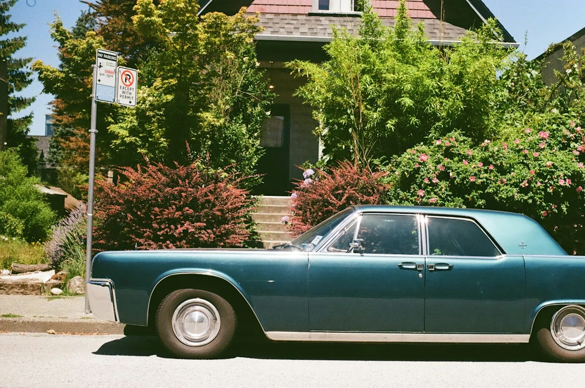 Blue car parked in front of a residential house