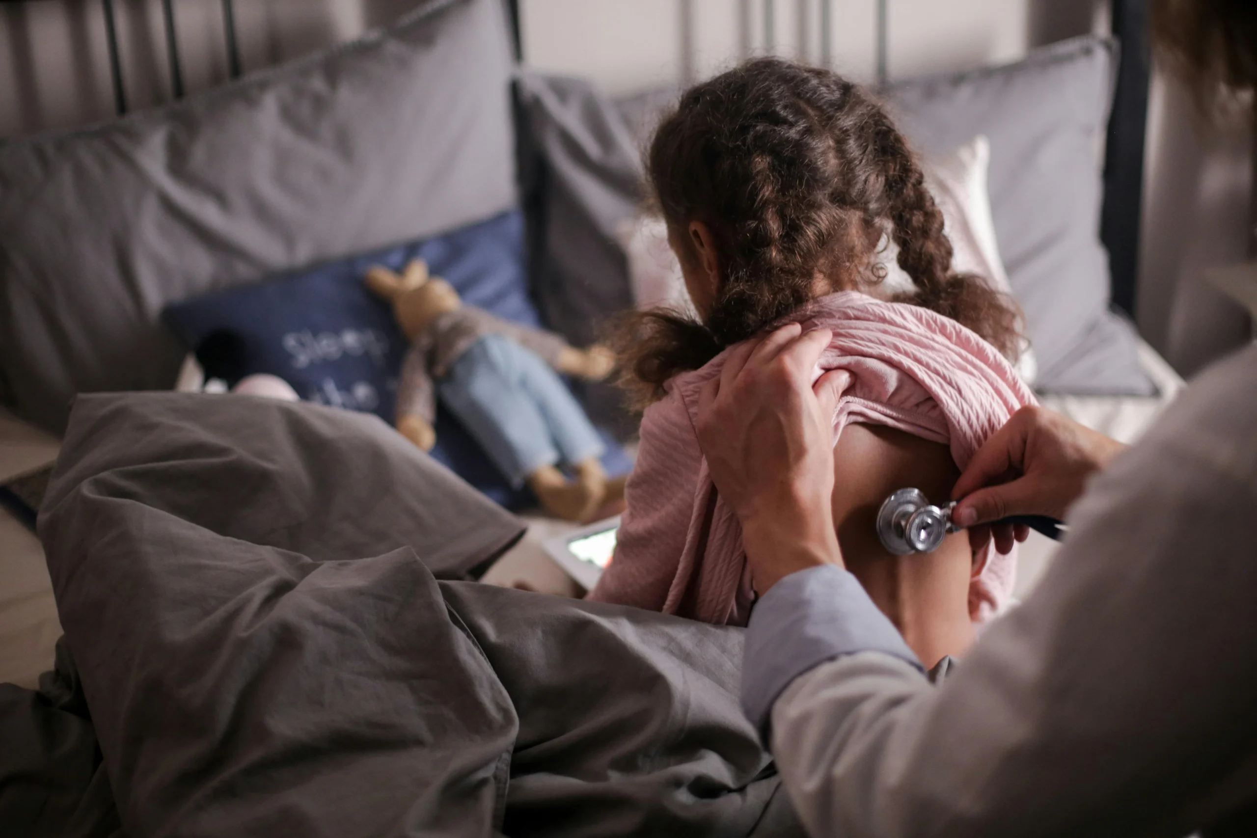 Doctor checking a child’s back with a stethoscope during a home health exam