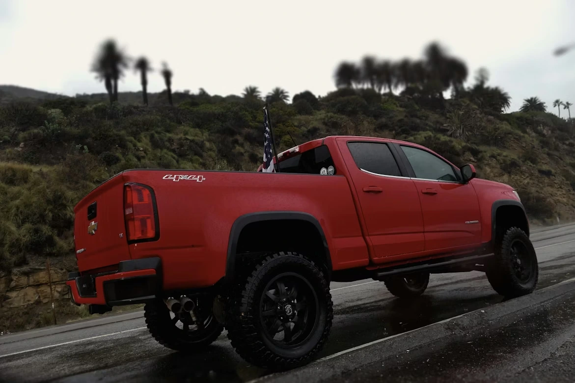 Red truck driving on a wet road in rural countryside