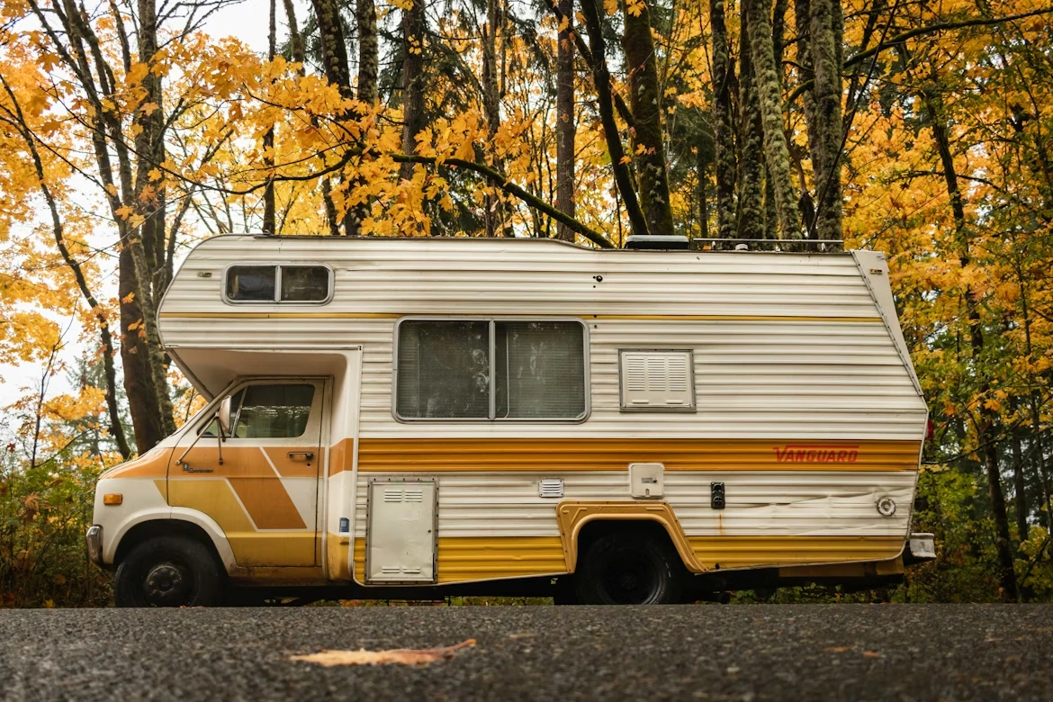 Abandoned RV parked on the side of a road during autumn