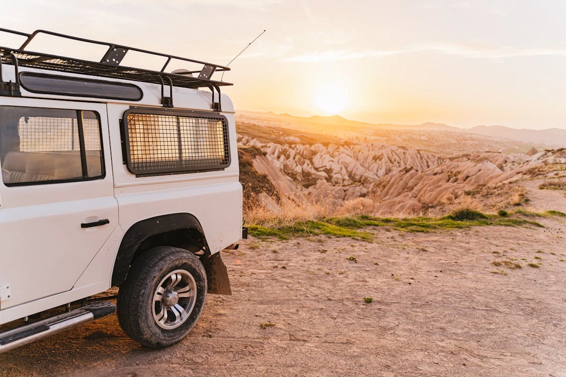 Off-road vehicle parked on a dirt road at sunset