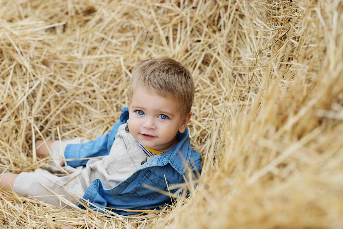 Young boy in a denim jacket lying on brown grass outdoors