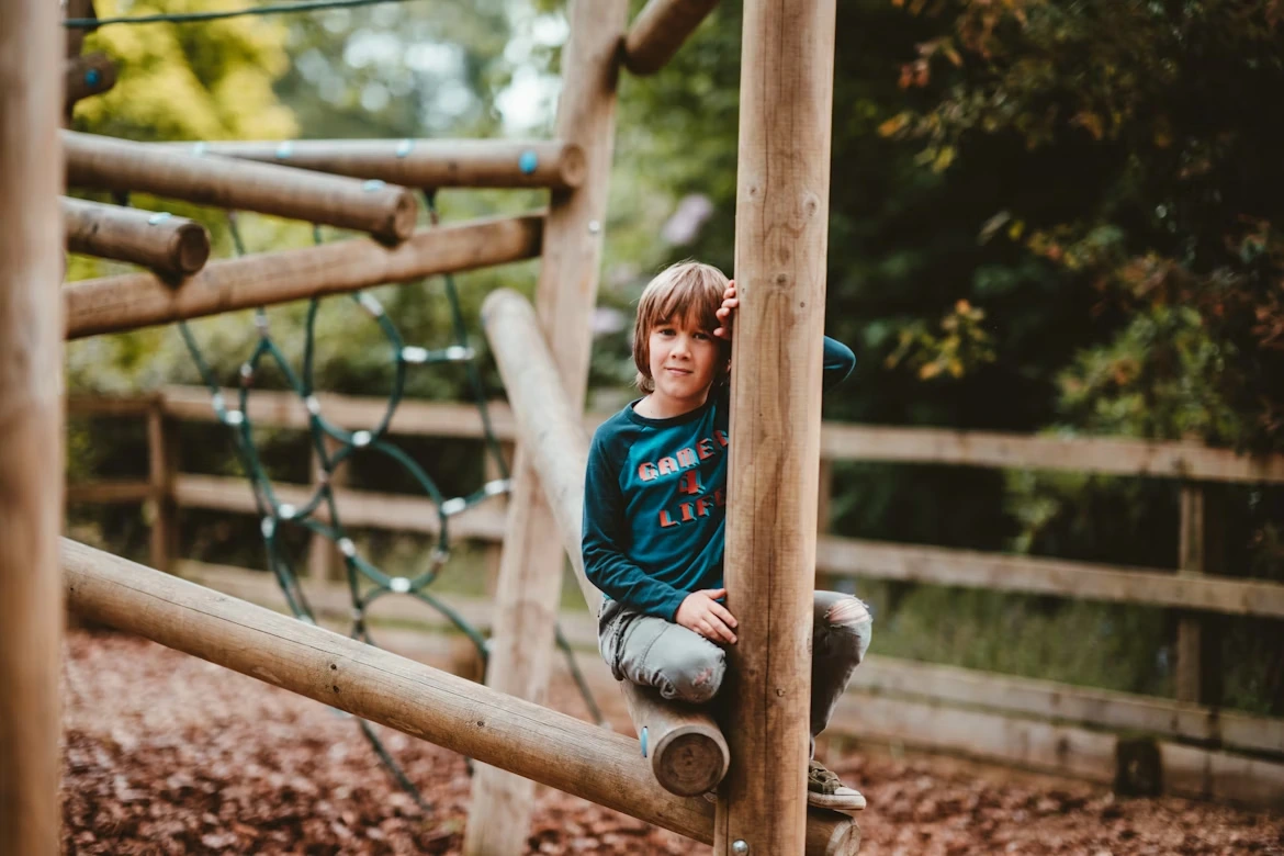 A young boy sitting on top of a wooden slide