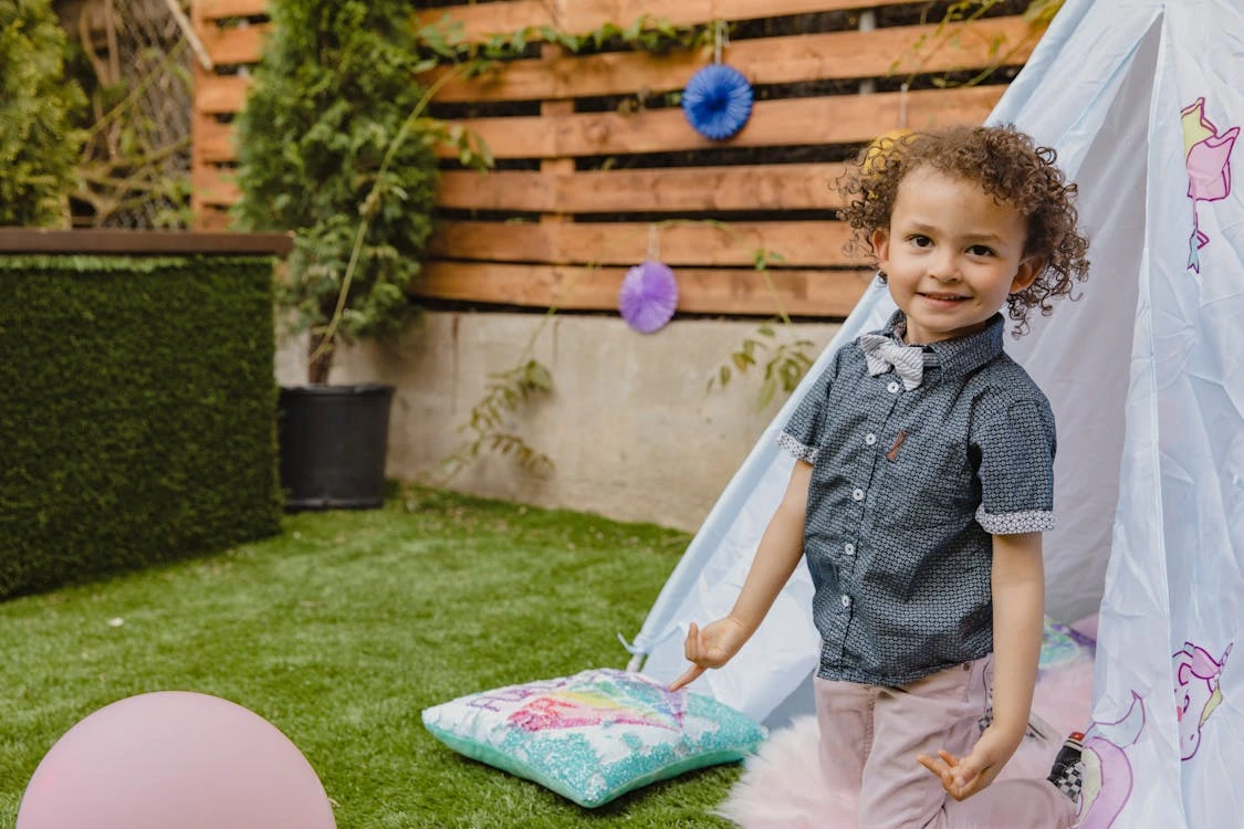 Adorable young boy in a polka dot polo shirt smiling outdoors