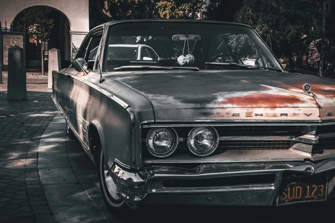 An old weathered car parked on a cobblestone street