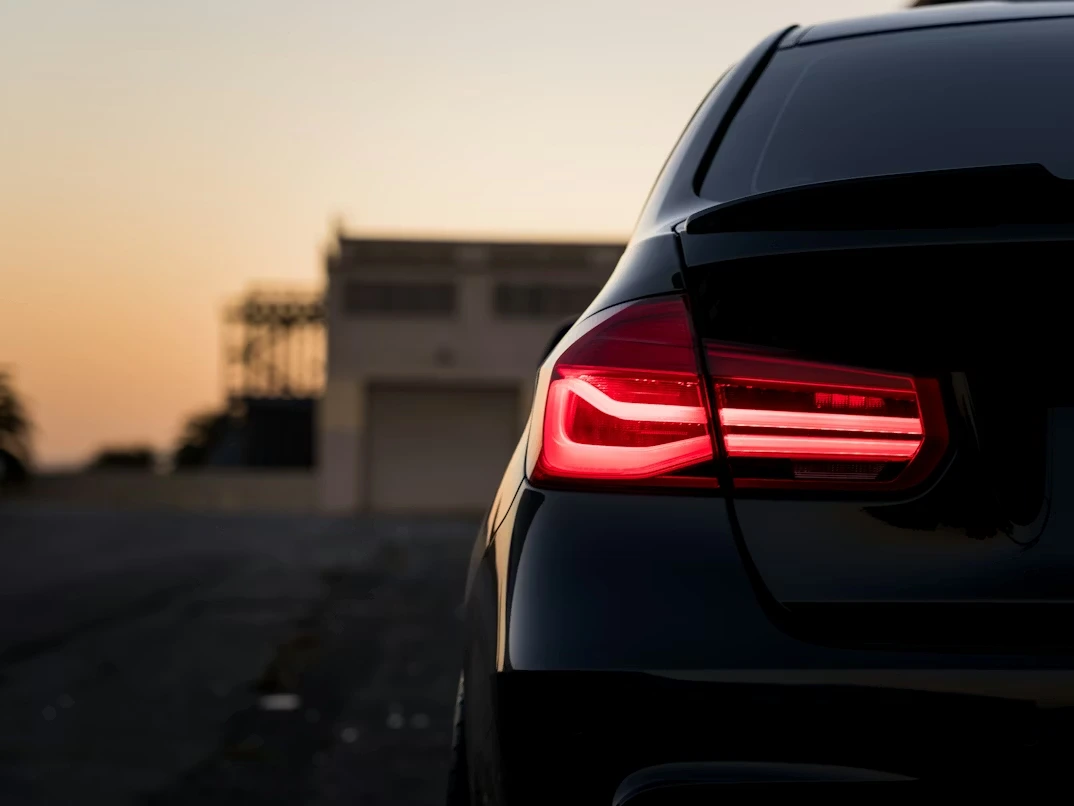 Black car on a road during sunset with glowing taillight