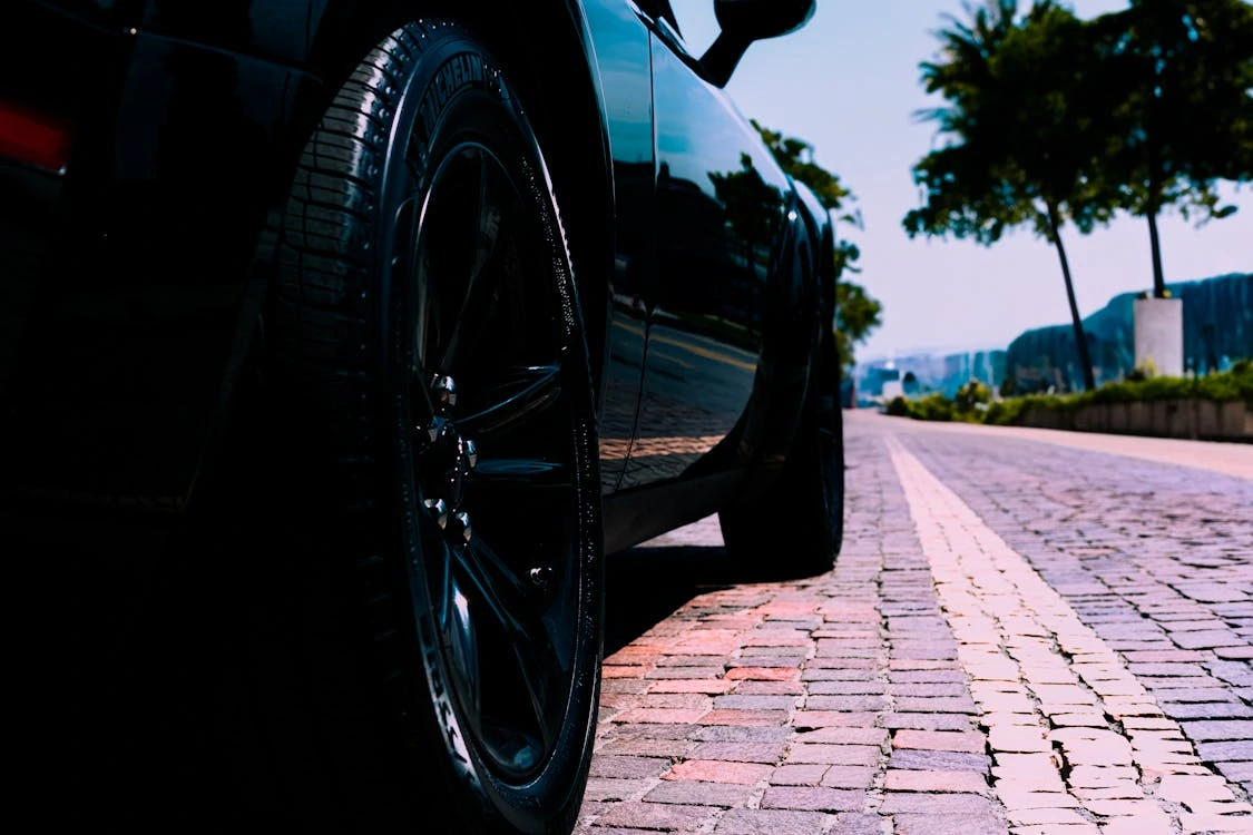 Close-up of a black car wheel on a cobblestone street, urban style