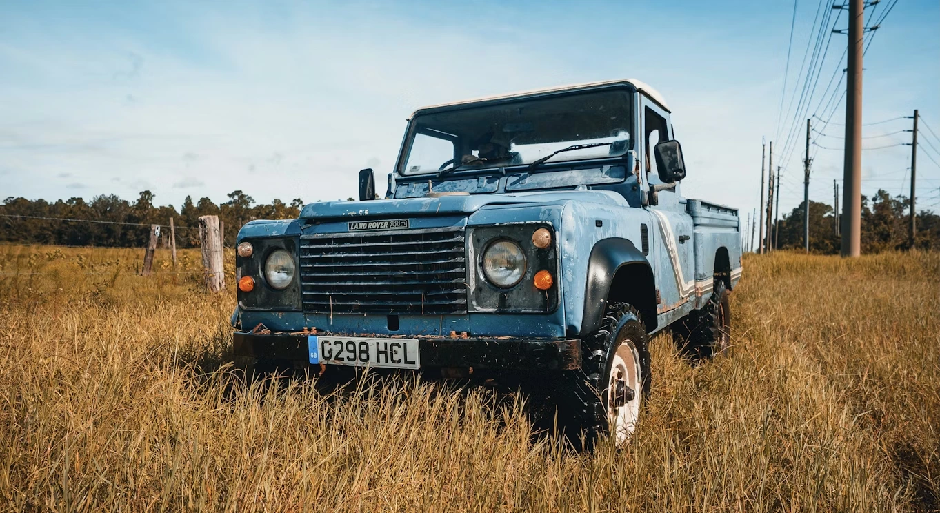 Blue Jeep Wrangler parked on a brown grass field