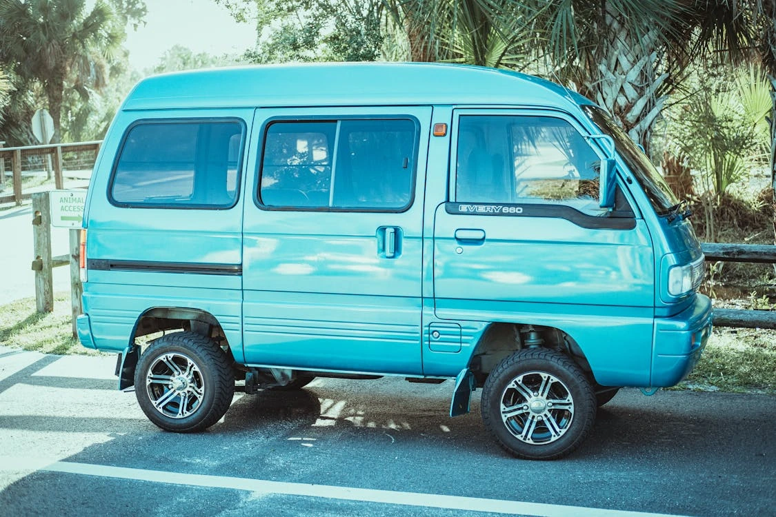 Blue minivan parked on a gray asphalt road