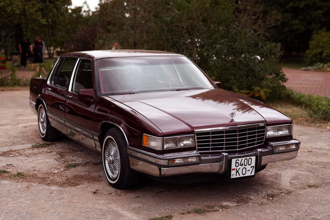 Brown Cadillac DeVille parked beside a tree