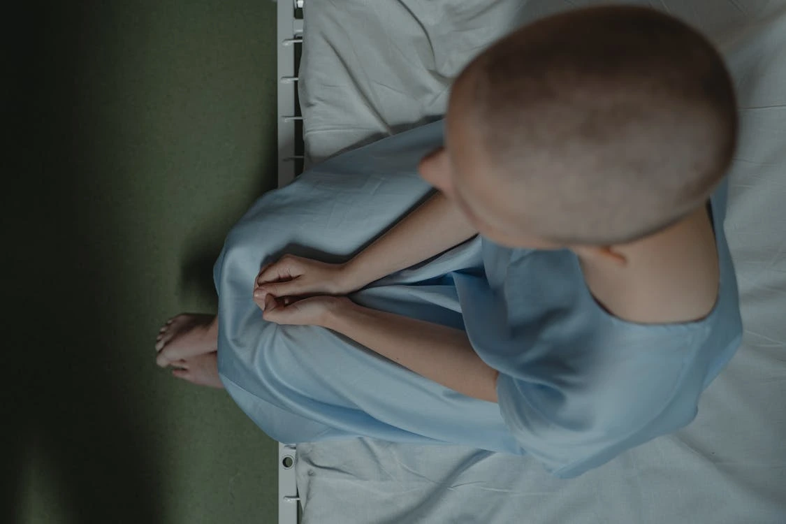 Pediatric cancer patient sitting on hospital bed