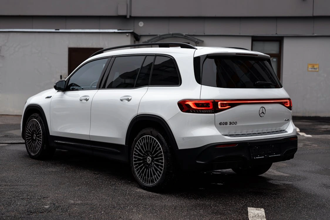 White luxury SUV parked on a wet urban street