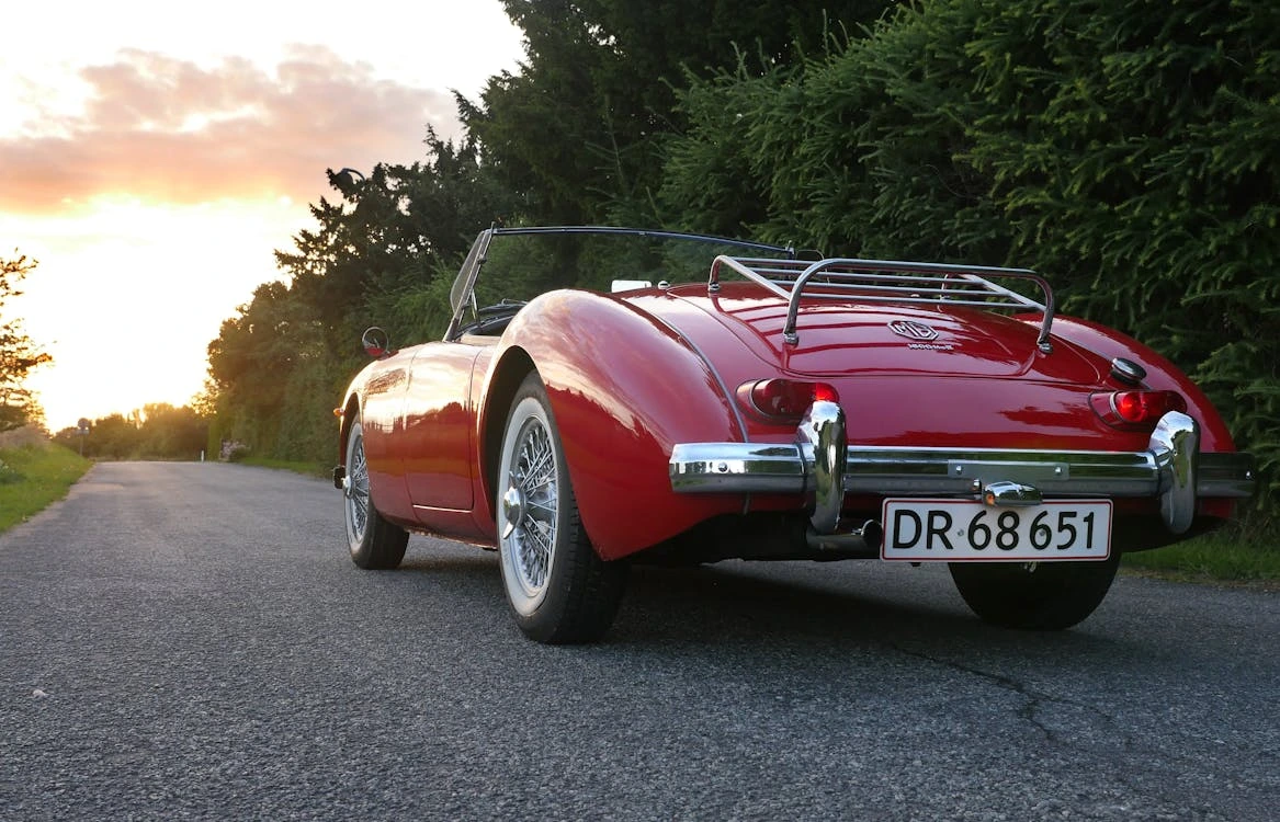 Classic red convertible on a scenic road at sunset