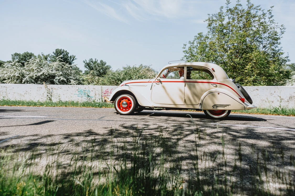 Classic vintage car driving down a sunny road