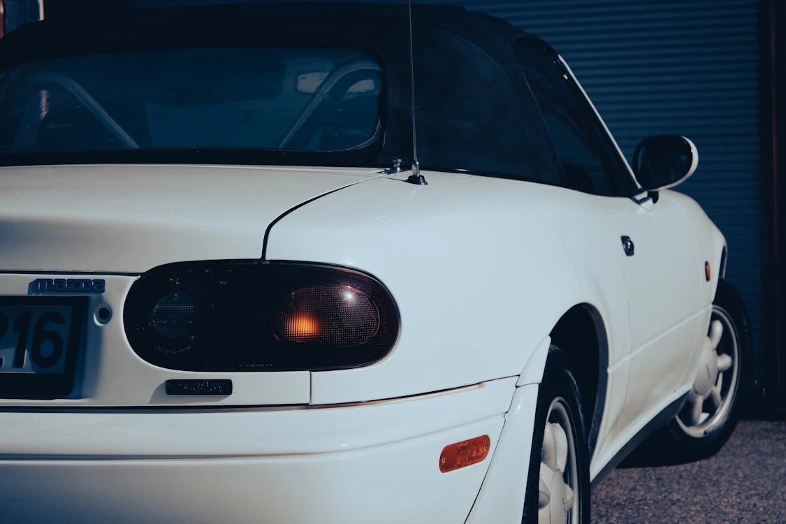 Close-up shot of a white car highlighting the grille and headlight