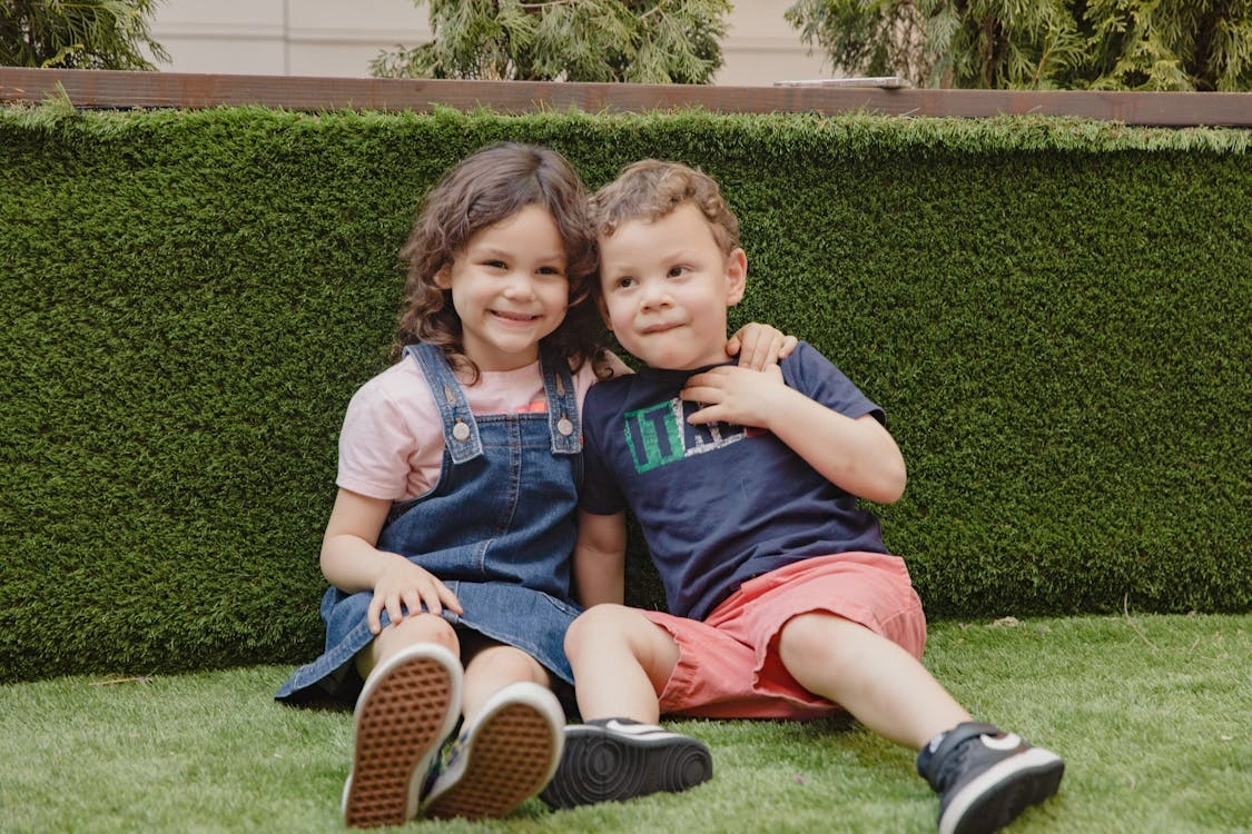 Cute children sitting on grass outdoors