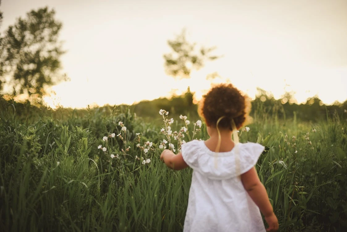 Girl standing beside a white flower field