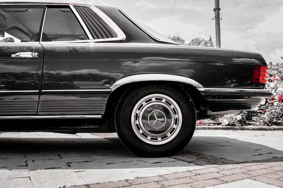 Grayscale photo of a vintage Mercedes-Benz driving on a road