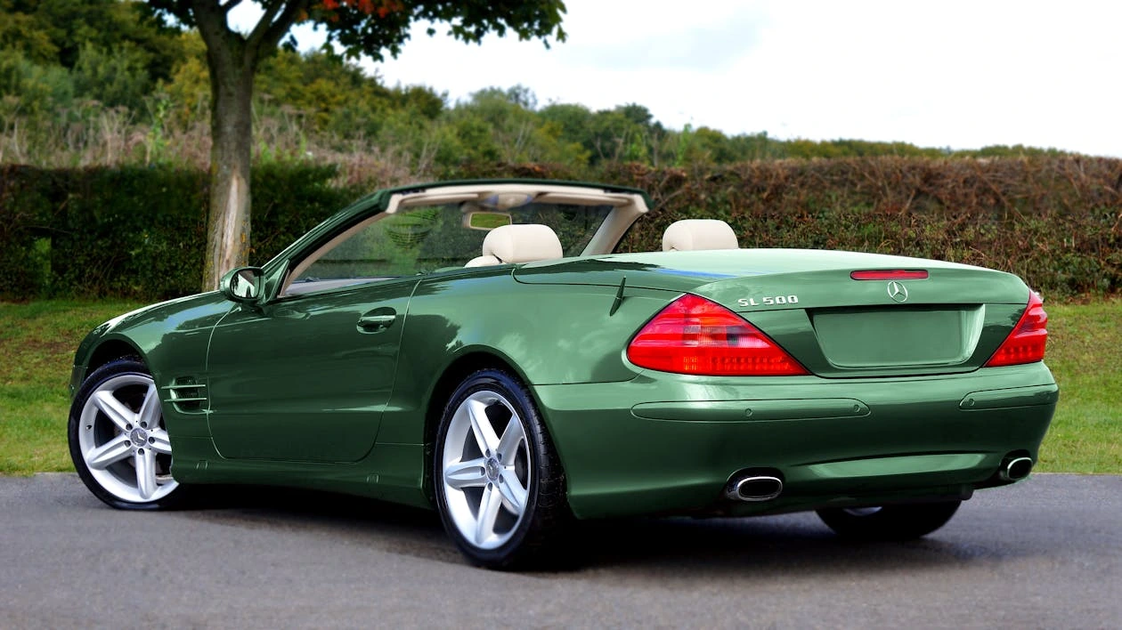 Classic green coupe parked outside a wooden house