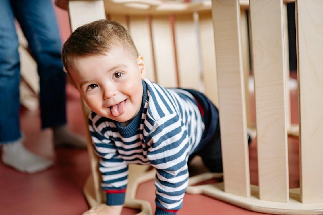 Little boy playing under a seesaw in a playground
