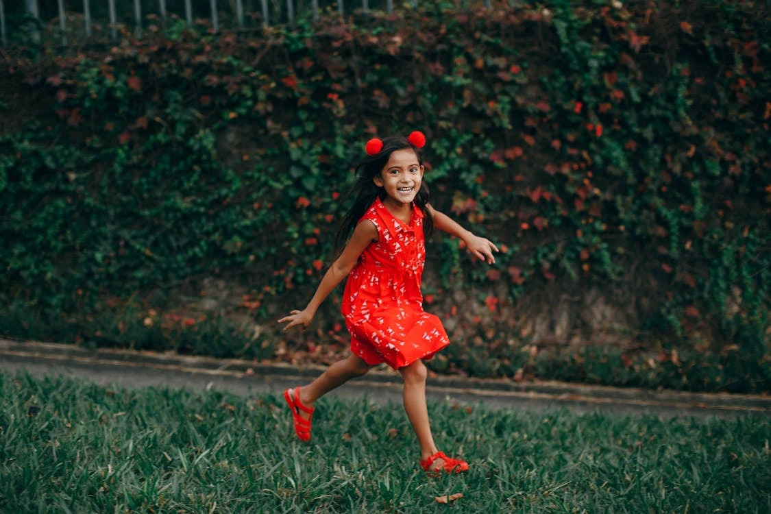 Little girl walking outdoors on a path with trees