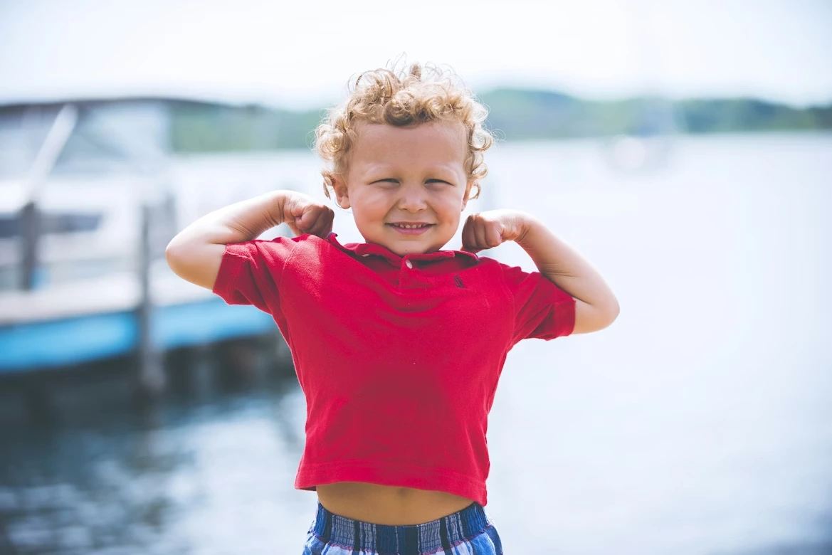 Happy boy standing near a dock on a sunny day