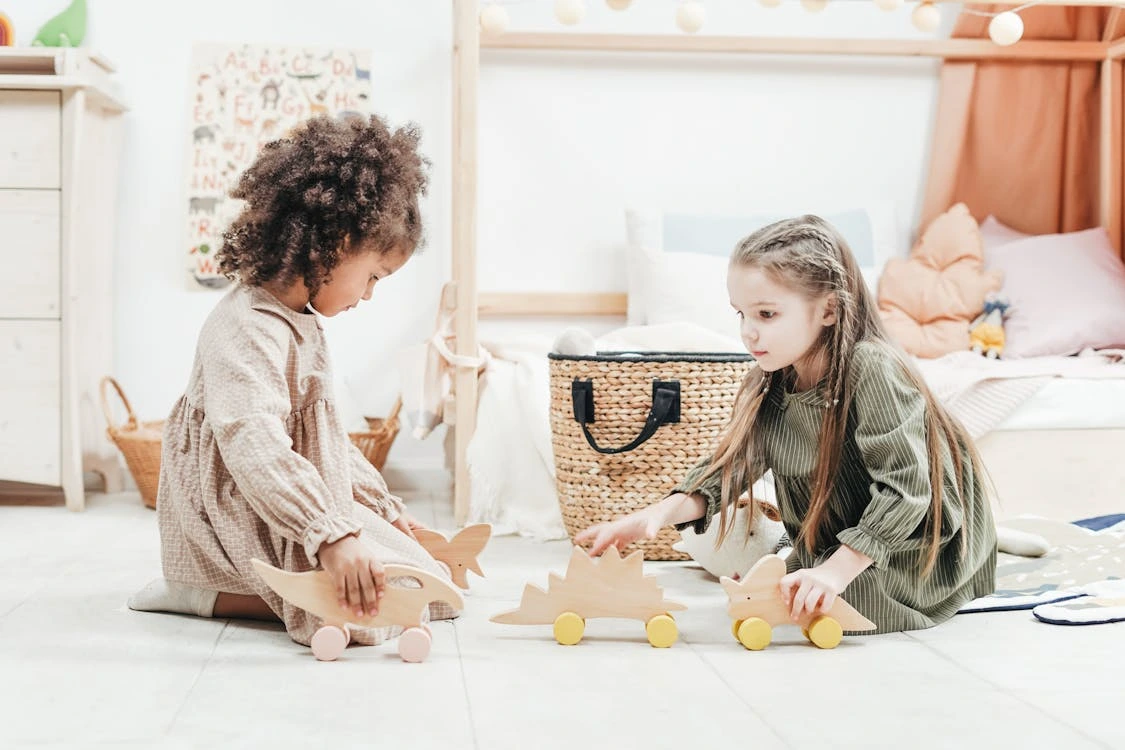 Photo of girls playing with wooden toys indoors