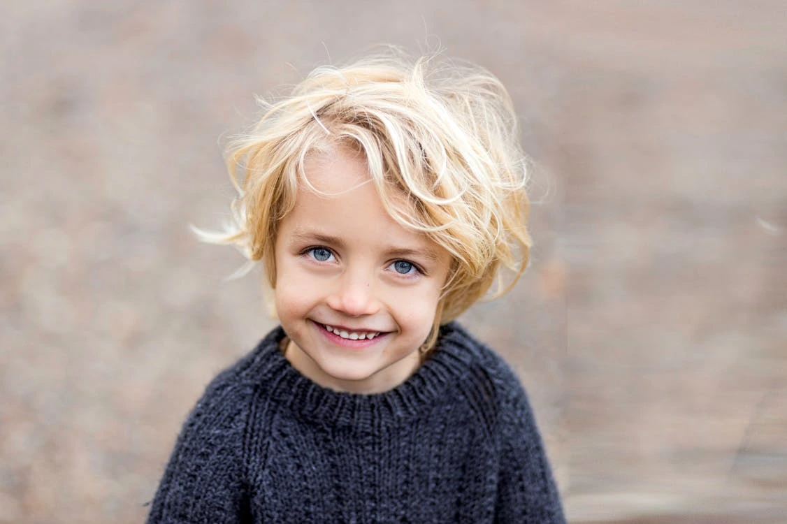 Portrait of a blonde child in a black knitted sweater