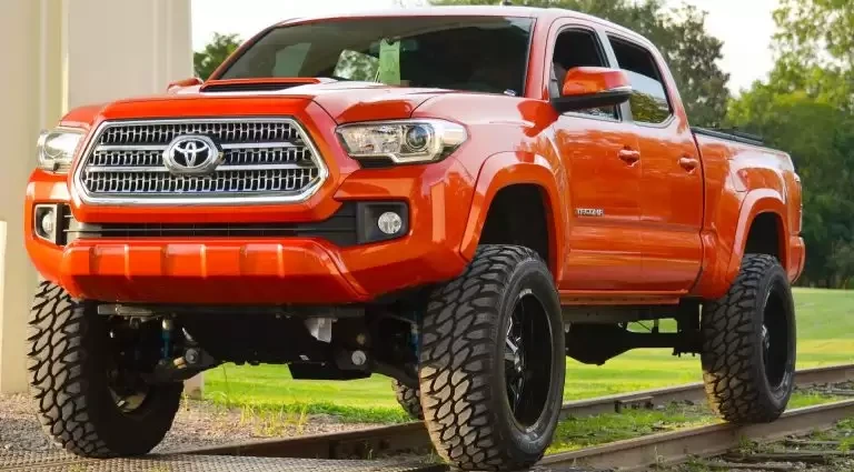 Red Chevrolet crew cab pickup truck parked in a forest