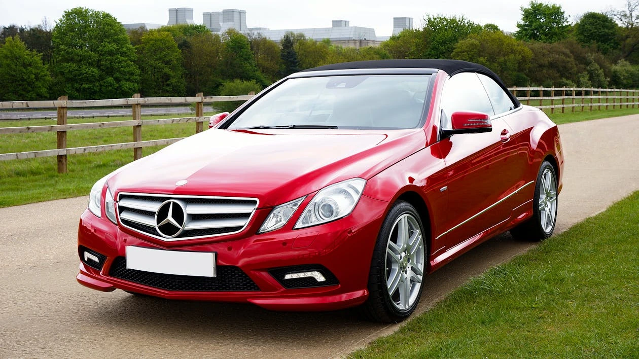 Red Mercedes-Benz sports car parked beside a green field