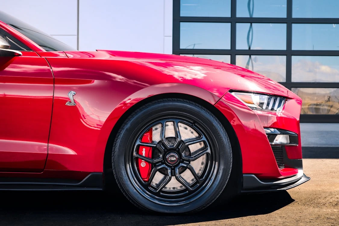 Red sports car with a Cobra logo on the side parked outdoors