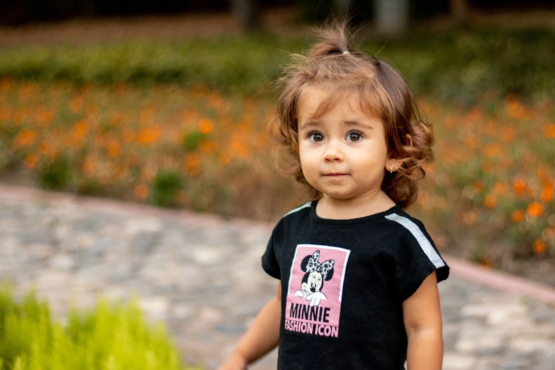 Selective focus photo of a cute kid with brown hair outdoors