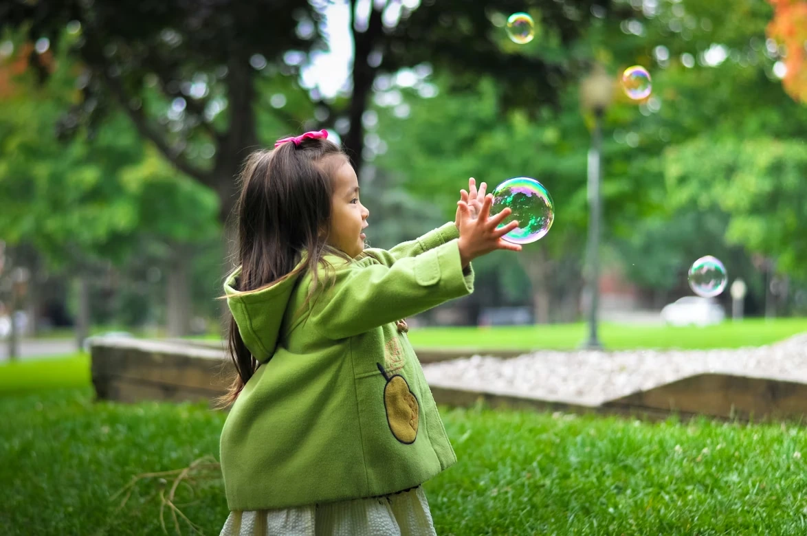 Selective photo of a girl holding bubbles